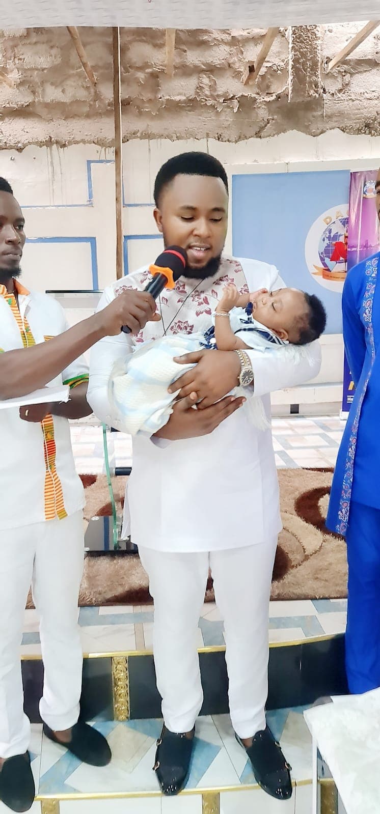 Prophet William Osei dedicating a baby with family alongside.