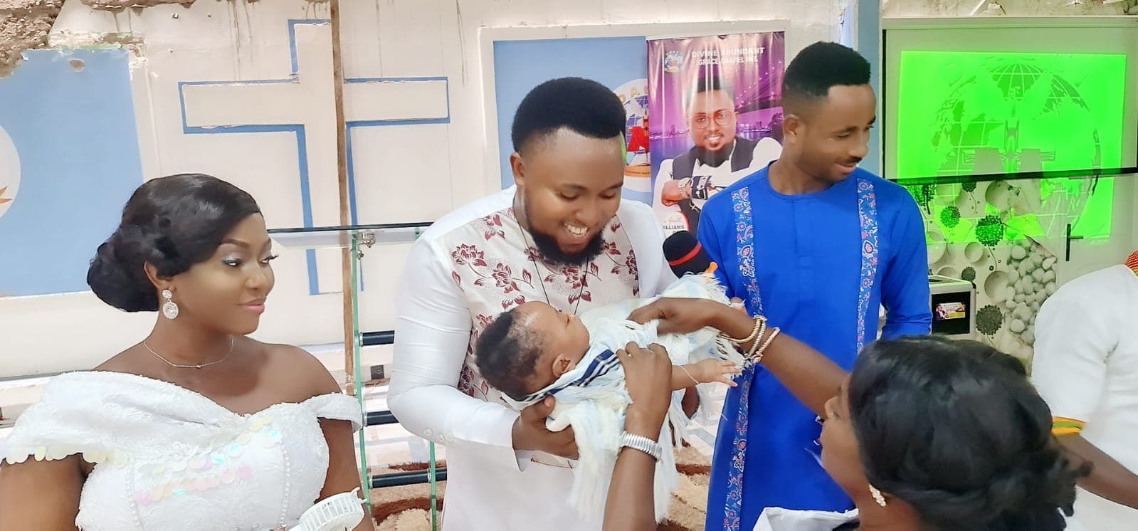 Prophet William Osei holding an infant during a baby dedication.