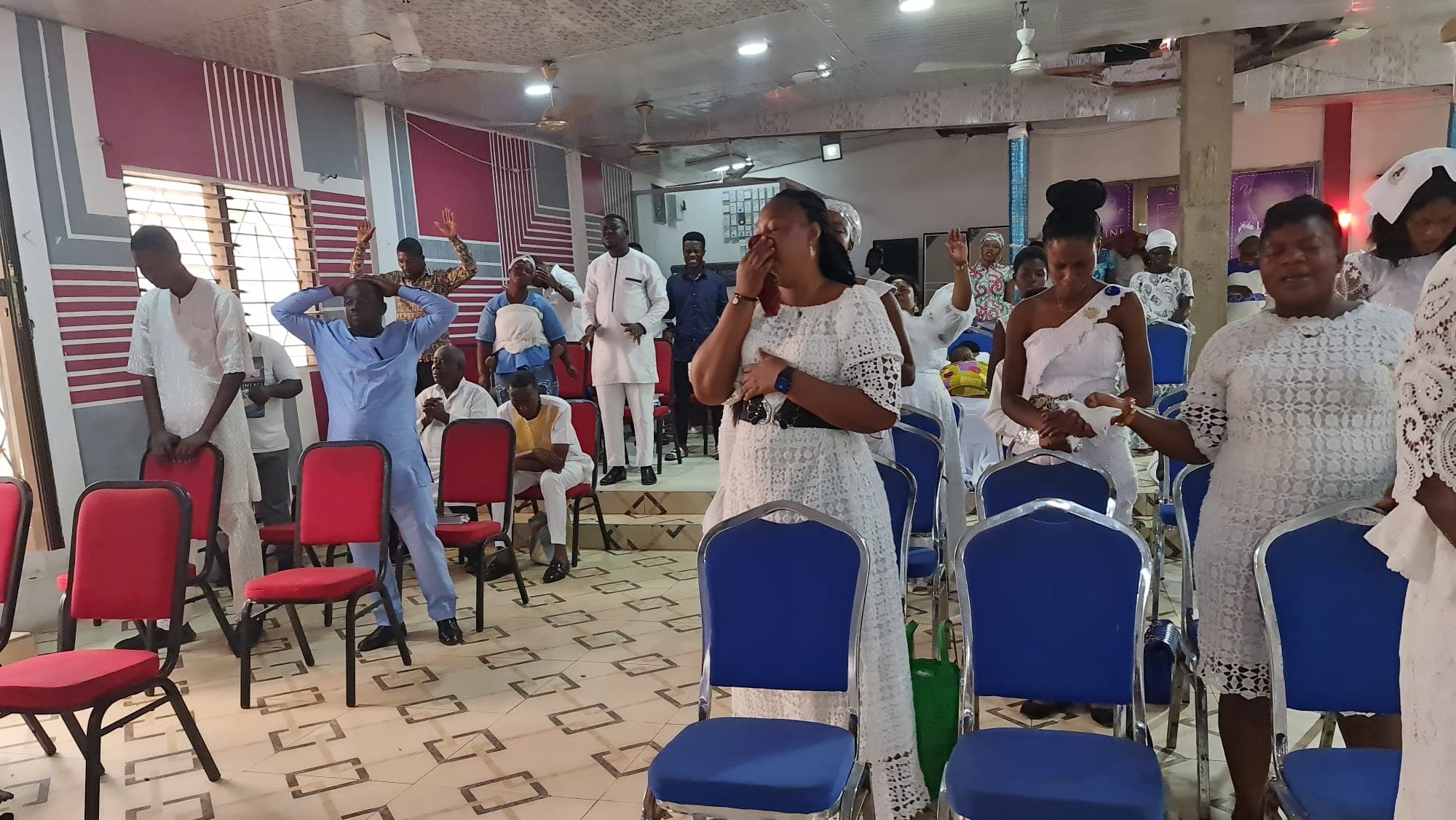 Congregants in prayer with hands raised at DAG Foundation.